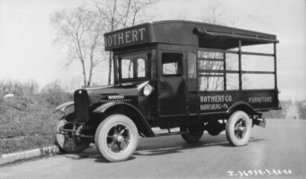 View towards the driver's side of a delivery truck parked along a curb. The sign painted on the side reads: "Rothert Co. Furniture."