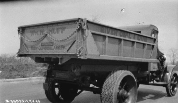 Rear view from right side of a coal delivery truck on a road. The sign painted on the back reads: "Wm. H. Huff" and "River Coal & Sand."