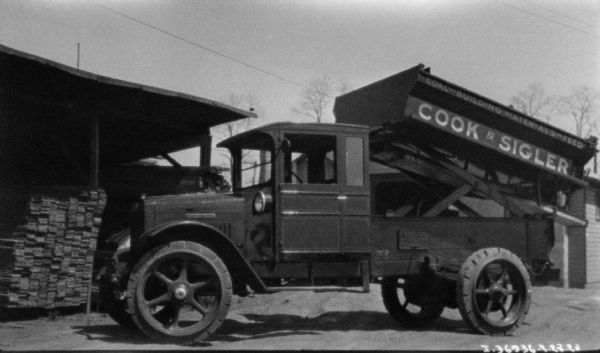 View towards the driver's side of a coal delivery truck. The sign painted on the side of the truck bed reads: "Cook & Sigler."