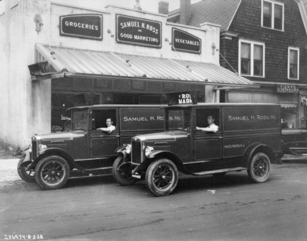 Two men are driving delivery trucks which are parked in front of a storefront for Samuel H. Ross, Inc.