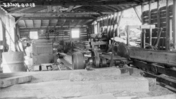 Interior view of a sawmill with an engine powering the saw.