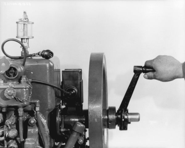 Assembly maintenance. View of a person (out of frame) whose hand is making adjustments on a 1 1/2 H.P. engine.