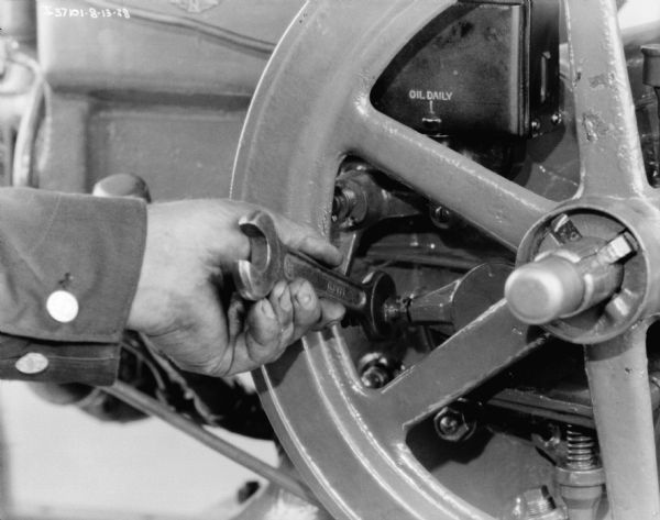 View of a person's hand using a wrench while making adjustments on a 1 1/2 H.P. engine.