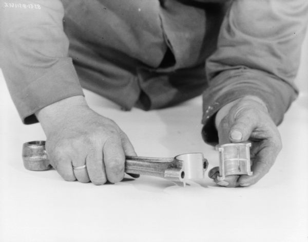 Close-up of a man's hands making adjustments to an engine assembly.