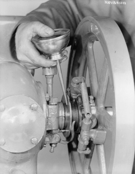 Close-up of a man's hands oiling a 1 1/2 H.P. engine with oil can.