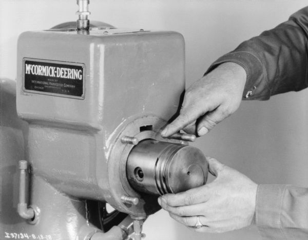 Close-up of a man's hand making adjustments making adjustments on a McCormick-Deering 1 1/2 H.P. engine.