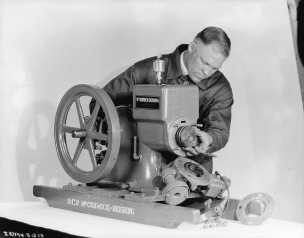 A man is demonstrating a repair on a McCormick-Deering 1 1/2 H.P. engine.