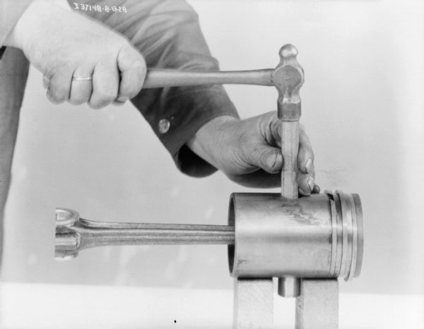 View of a man (head out of frame) using tools to maintain a 1 1/2 H.P. engine.