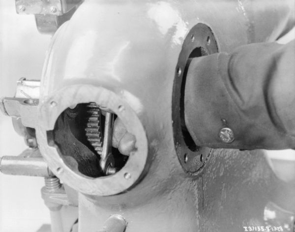 Close-up of a man's hand making adjustments on a McCormick-Deering 1 1/2 H.P. engine.