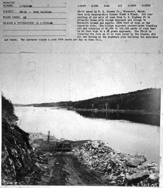 Subject: "TD-18 — Road Building." Where Taken: "NE." Information with photograph reads: "TD-18 owned by W.H. Hinman Co., Wicasset, Maine. Used with Bucyrus-Erie Grader Blade & Winch. Job consisting of one mile of road from U.S. Highway #1 to Atlantic Ocean with bridge approach and bridge to Westport Island and approx. 2200 feet of road on the opposite side. The bridge approach necessitates blasting out and clearing of 80,000 to 100,000 yards of rock that is 60 feet high to a 9% grade approach. The TD-18 is clearing the rock as it is torn loose by the blasts, did all the dozing on the highways plus building the shoulders and banks. The operator claims a good 6700 yards per day on dump fill."