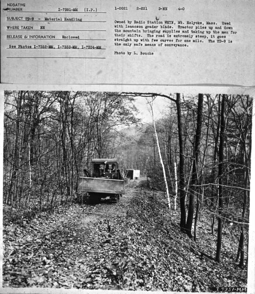 Subject: "TD-9 — Material Handling." Where Taken: "NE." Information with photograph reads: "Owned by Radio Station WHYN, Mt. Holyoke, Mass. Used with Isaacson grader blade. Tractor plies up and down the mountain bringing supplies and taking up the men for their shifts. The road is extremely steep, it goes straight up with few curves for one mile. The TD-9 is the only safe means of conveyance. Photo by L. Bouche."	