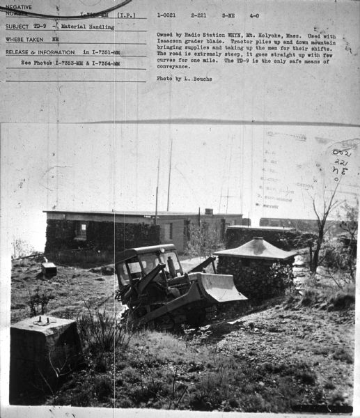 Subject: "TD-9 — Material Handling." Where Taken: "NE." Information with photograph reads: "Owned by Radio Station WHYN, Mt. Holyoke, Mass. Used with Isaacson grader blade. Tractor plies up and down the mountain bringing supplies and taking up the men for their shifts. The road is extremely steep, it goes straight up with few curves for one mile. The TD-9 is the only safe means of conveyance. Photo by L. Bouche." 	