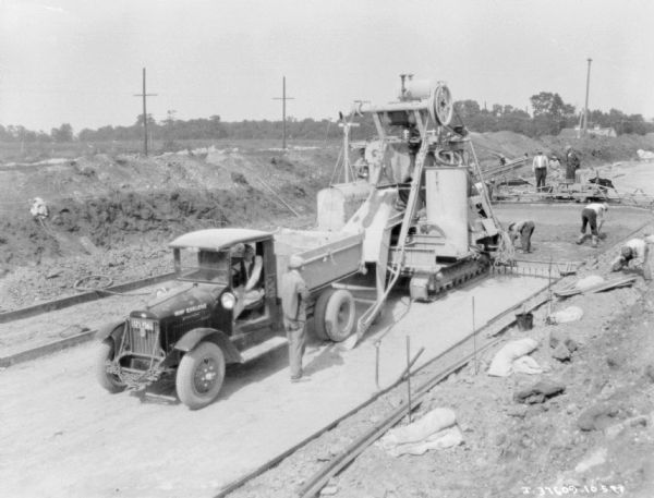 Slightly elevated view of men working with a truck and other machinery on highway construction.