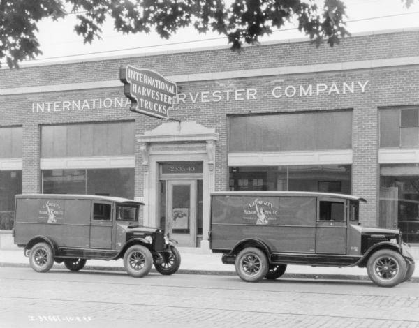 View across street towards two trucks parked in front of the building for International Harvester Company. The signs painted on the trucks read: "Liberty Macaroni Mfg. Co., 119 Wilkeson St., Buffalo, N.Y."
