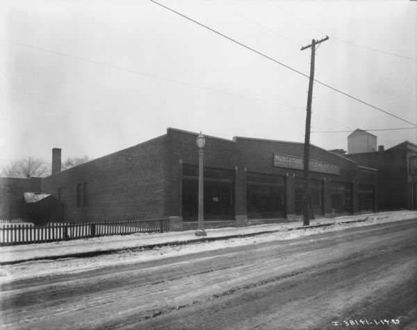 View across road towards a dealership. The sign on the front reads: "Muscatine Implement Co."