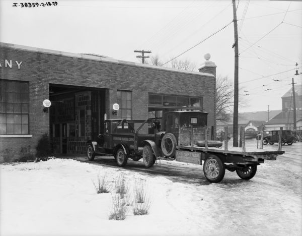"Red Baby" towing a truck into a repair shop. The sign on the truck being towed reads: "The McKenzie Lumber & Coal Co."