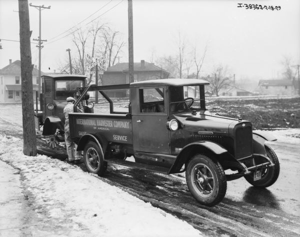 "Red Baby" towing truck into a repair shop. Snow is on the ground. There is a railroad crossing sign in the background.