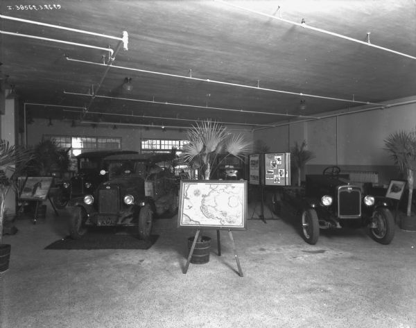 "Truck That Crossed The Sahara" is on display in a dealership. In the foreground is a map on an easel.