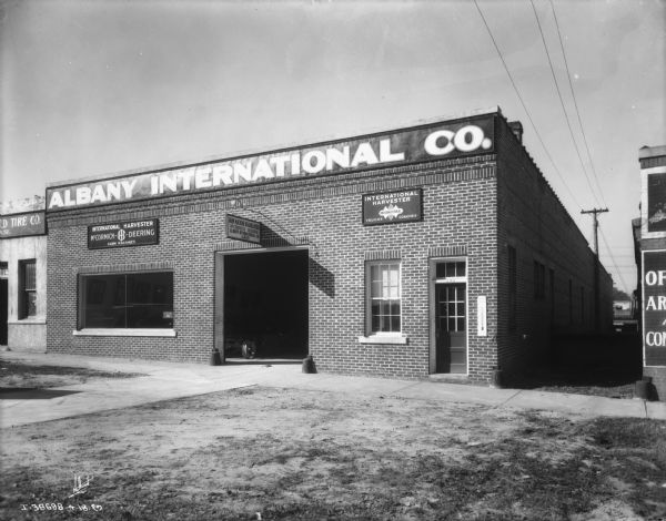 View of the front of a brick building. Along the top near the roof is a sign that reads: "Albany International Co."