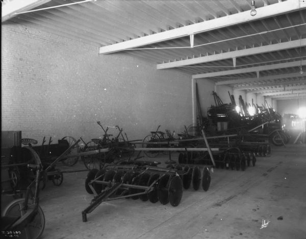 View of agricultural implements on display on the floor of a dealership.