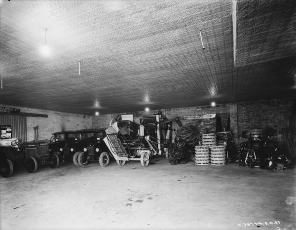 Interior view of the service department. Along the back walls are tractors, trucks, various parts and other equipment.