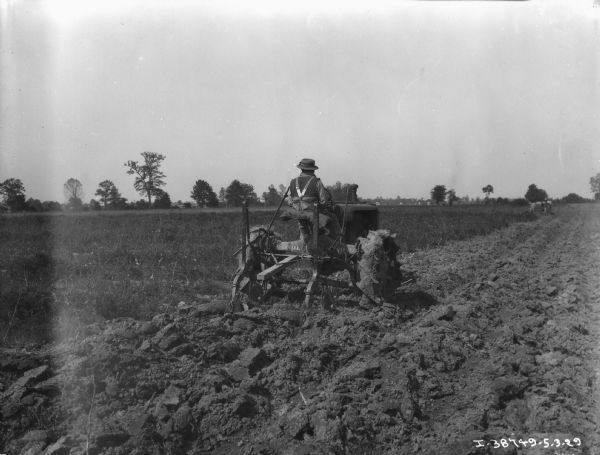Rear view of a man plowing in a field.
