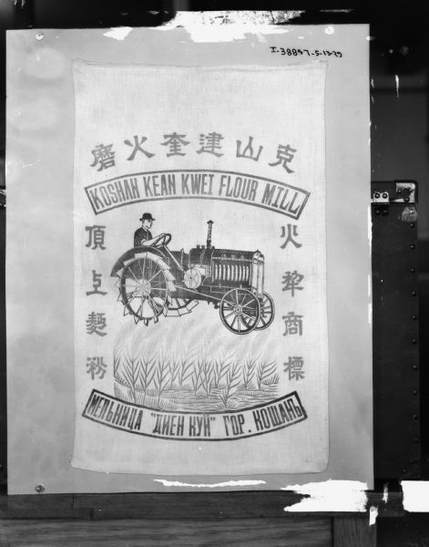 Chinese flour sack with a design of a man driving a tractor. The text at the top reads: "Koshan Kean Kwei Flour Mill."