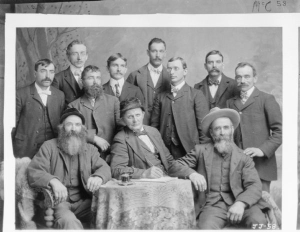 Copy of formal portrait of men posing in front of a painted backdrop.