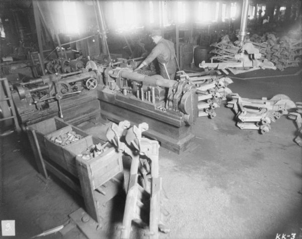 Elevated view of a man guiding molded machine parts on a conveyor.