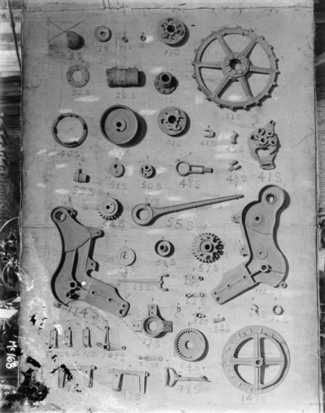 Parts for a machine are displayed on a board with part numbers written below each one at McCormick Works.
