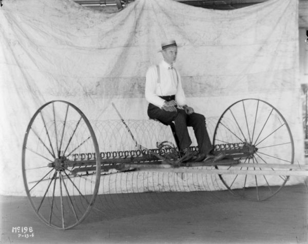 View of a man posing on a dump rake, with a white colored sheet in the background as a backdrop. Double exposure.