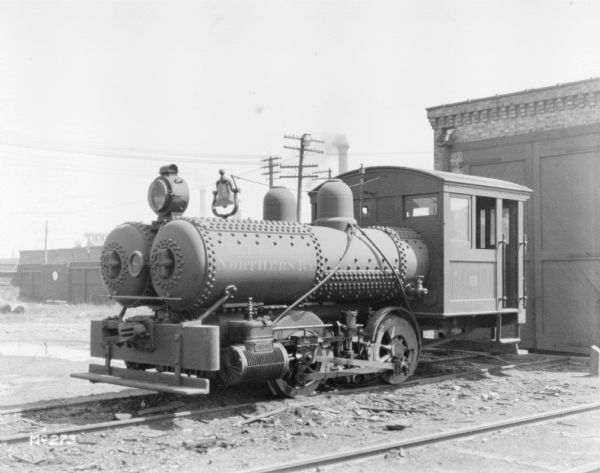 Northern Railroad Engine on railroad tracks at McCormick Works, parked in front of the closed doors of a building.