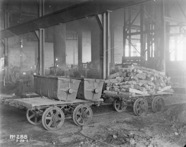 Carts sitting inside a foundry area, loaded with wood and molds.