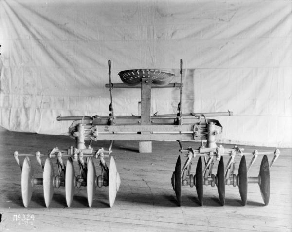 Rear view of a disk harrow indoors at McCormick Works. There is a light-colored backdrop in the background.