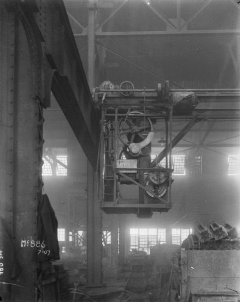 Overhead gear driven delivery system in a factory at McCormick Works. Windows are along the wall in the background.