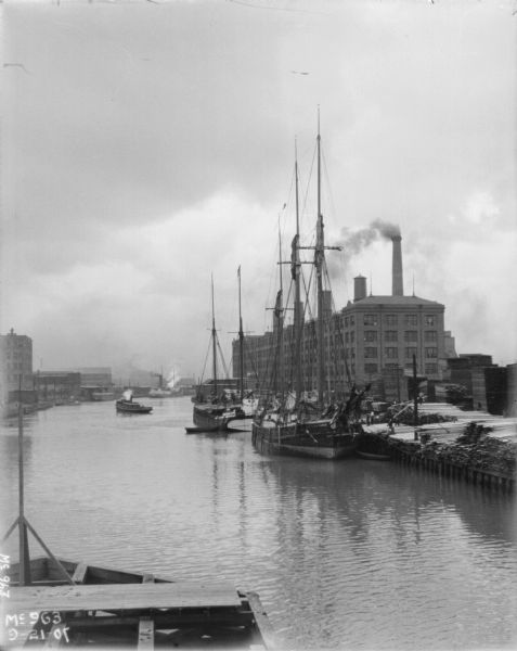 View of clipper ships at waterfront at McCormick Works. Stacks of lumber are near the wharf on the right.