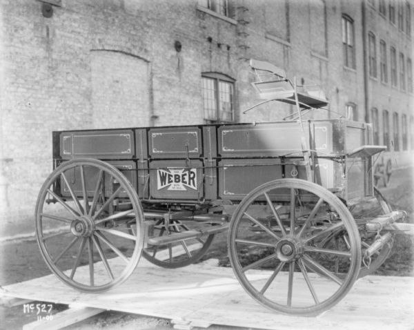 Right side view of a Weber wagon with wagon box set up on a wooden pallet outdoors at McCormick Works.
