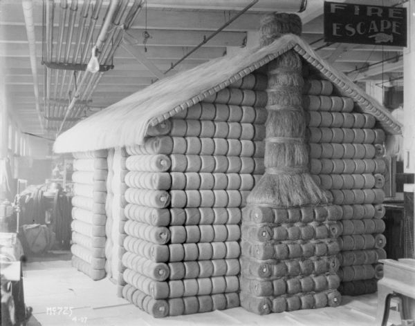 Twine Balls arranged into a house indoors at McCormick Works. There is a chimney on one wall, and a door on the left side.