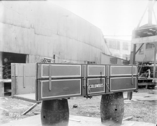 A Columbus wagon box set up on two barrels outdoors at McCormick Works.