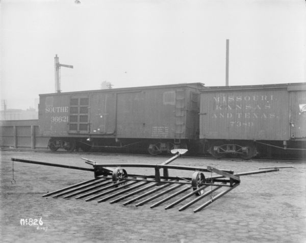 View of a Hay Stacker outdoors in a yard at McCormick Works. There are railroad cars in the background.
