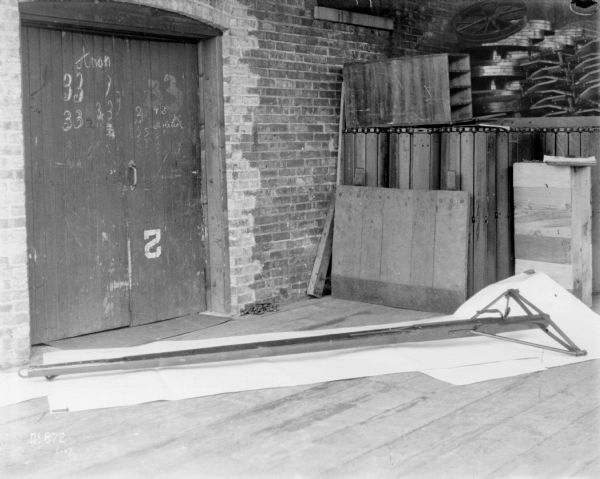 An evener is on a factory floor indoors at McCormick Works. There is a wooden door in a brick wall in the background.