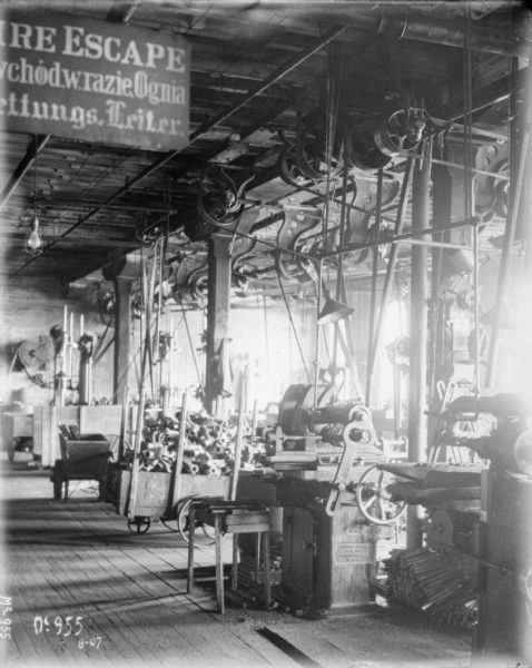 Work area, with metal machines, and a fire escape sign in three languages at McCormick Works.