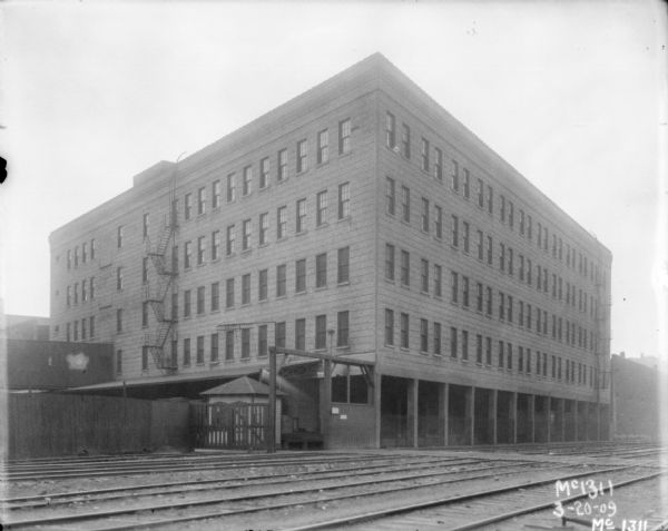 View across railroad tracks towards factory buildings.