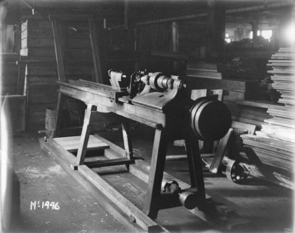 Finishing machine in a factory building. Stacks of lumber are in the background.