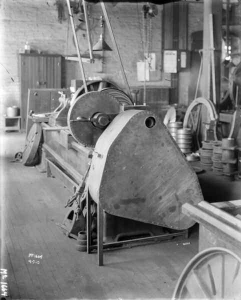 View of a lathe with a safety guard indoors in a factory building at McCormick Works.