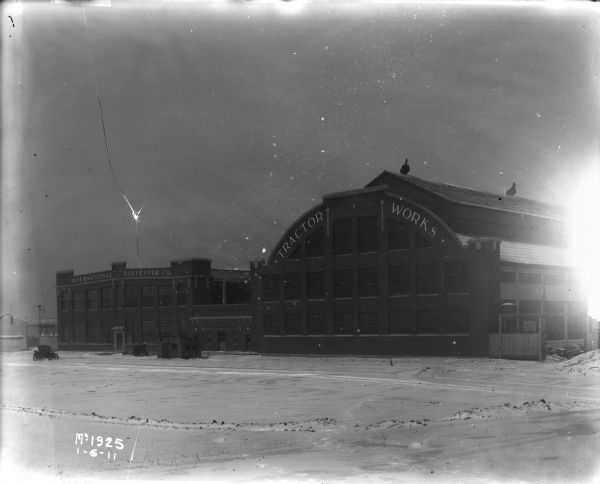 Exterior view of the International Harvester Tractor Works plant. Snow is on the ground. An automobile is parked on the left.