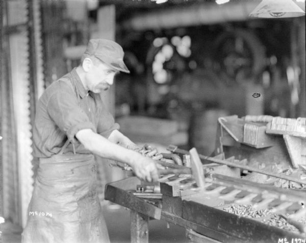 Employee finishing mower blade indoors at McCormick Works.