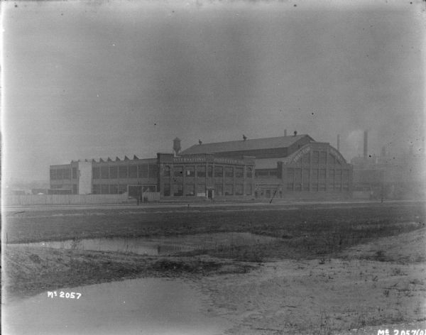 View across wet field towards the International Harvester Company and Tractor Works buildings.