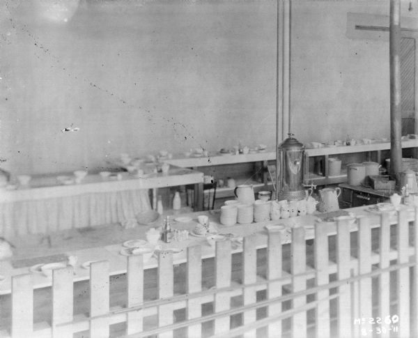 Dining room, with tables set for dinner. There is a fence in the foreground.