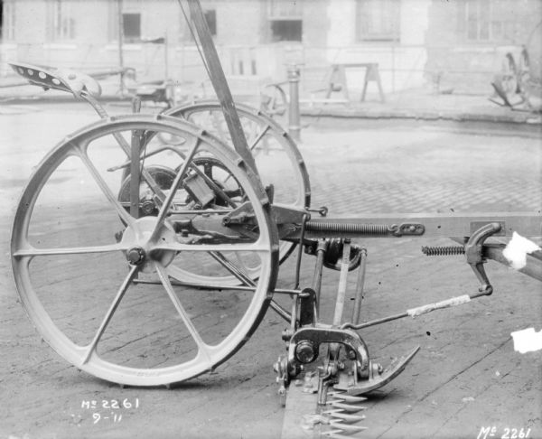 Mower outdoors in the yard at McCormick Works. There is a factory building in the background.